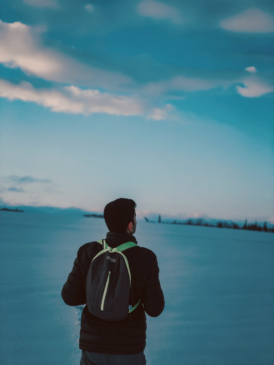 Back View of a Man Carrying His Back Pack in Front of Blue Ocean